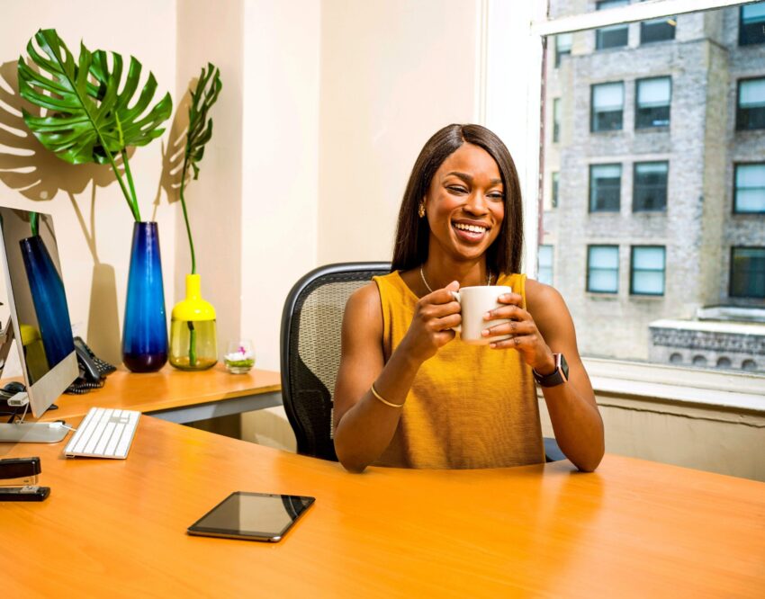Woman Smiling at Desk with Coffee